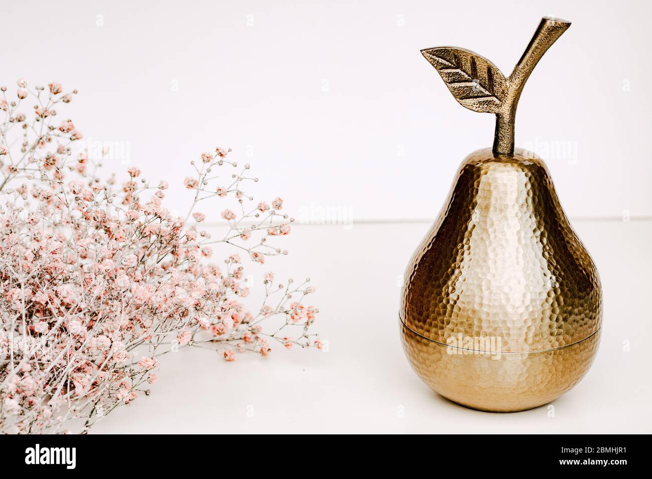 Ornement de poire dorée, boîte à bijoux dorée sur fond blanc, avec bannière de site de fleurs de souffle de Peach Babys Banque D'Images