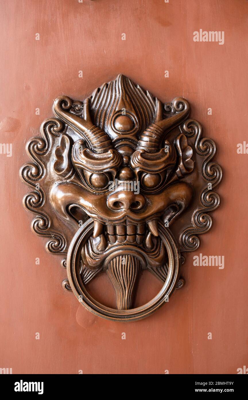 Porte en métal de style chinois traditionnel sur une porte en bois peinte en rouge Banque D'Images