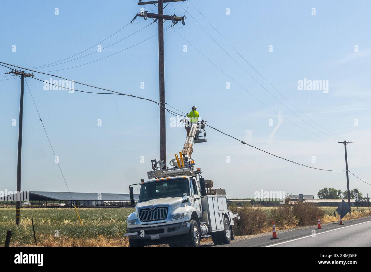 Un lineman AT&T supporte un câble qui a été décassé et qui est suspendu trop bas Banque D'Images