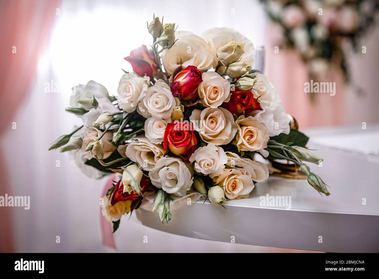 beau bouquet délicat de fleurs de mariage avec roses et ranuncules. Un  magnifique bouquet de roses blanches, roses et rouges se trouve sur une  table dans une chambre avec Photo Stock -