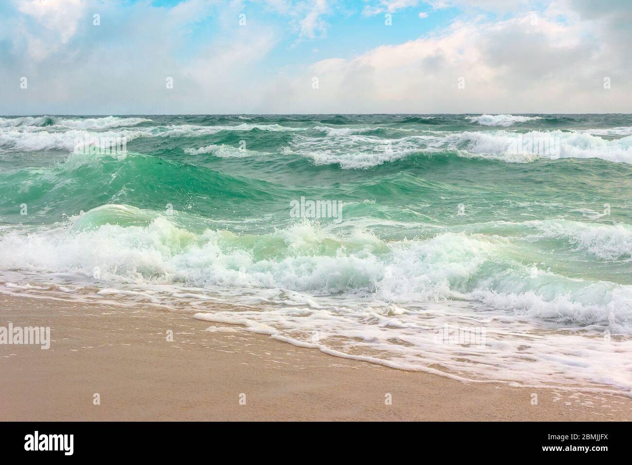 tempête sur la plage de sable. paysage océanique spectaculaire avec ciel nuageux. eau agitée et vagues écrasant Banque D'Images