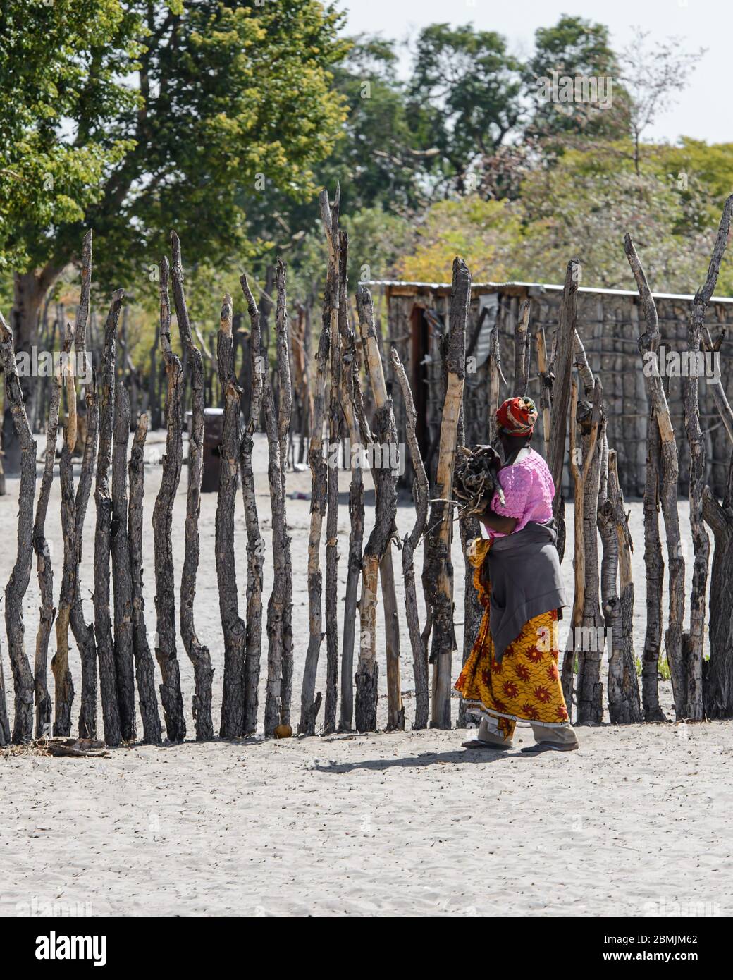 Femme avec des vêtements colorés et un serre-tête, marchant vers son village près du parc national d'Etosha en Namibie, Afrique Banque D'Images