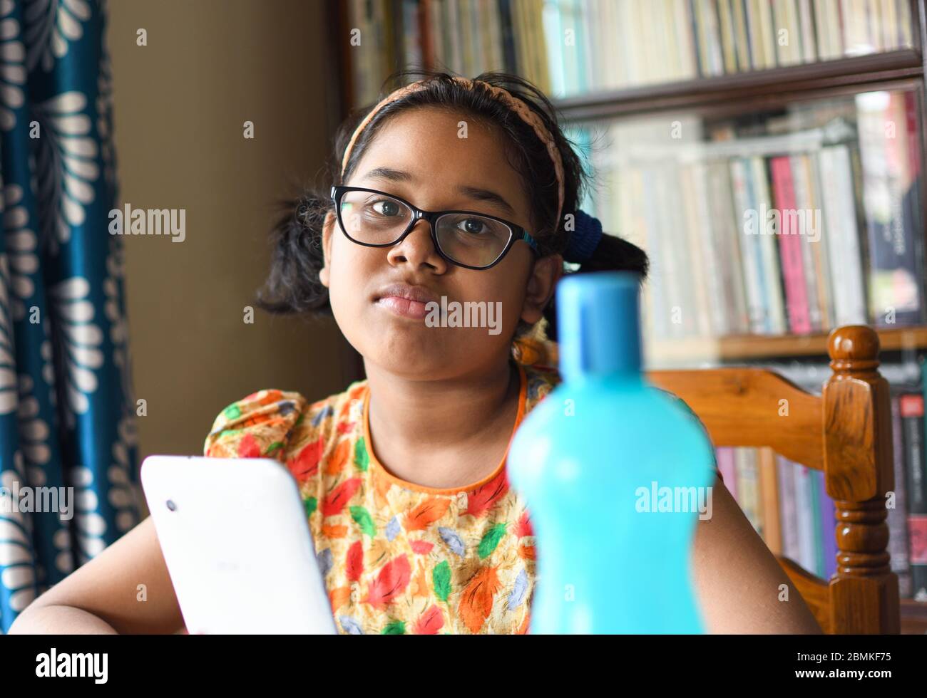 Petite fille indienne étudie à la maison en maintenant la distance sociale pendant la période de verrouillage pour Covid-19. Banque D'Images