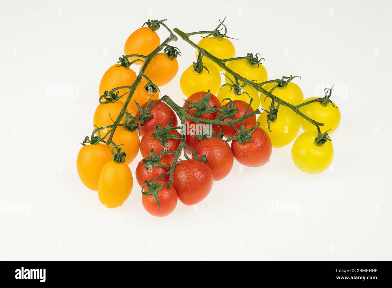 tomates cerises fraîches rouges, jaunes et orange sur fond blanc. tomates mouillées Banque D'Images
