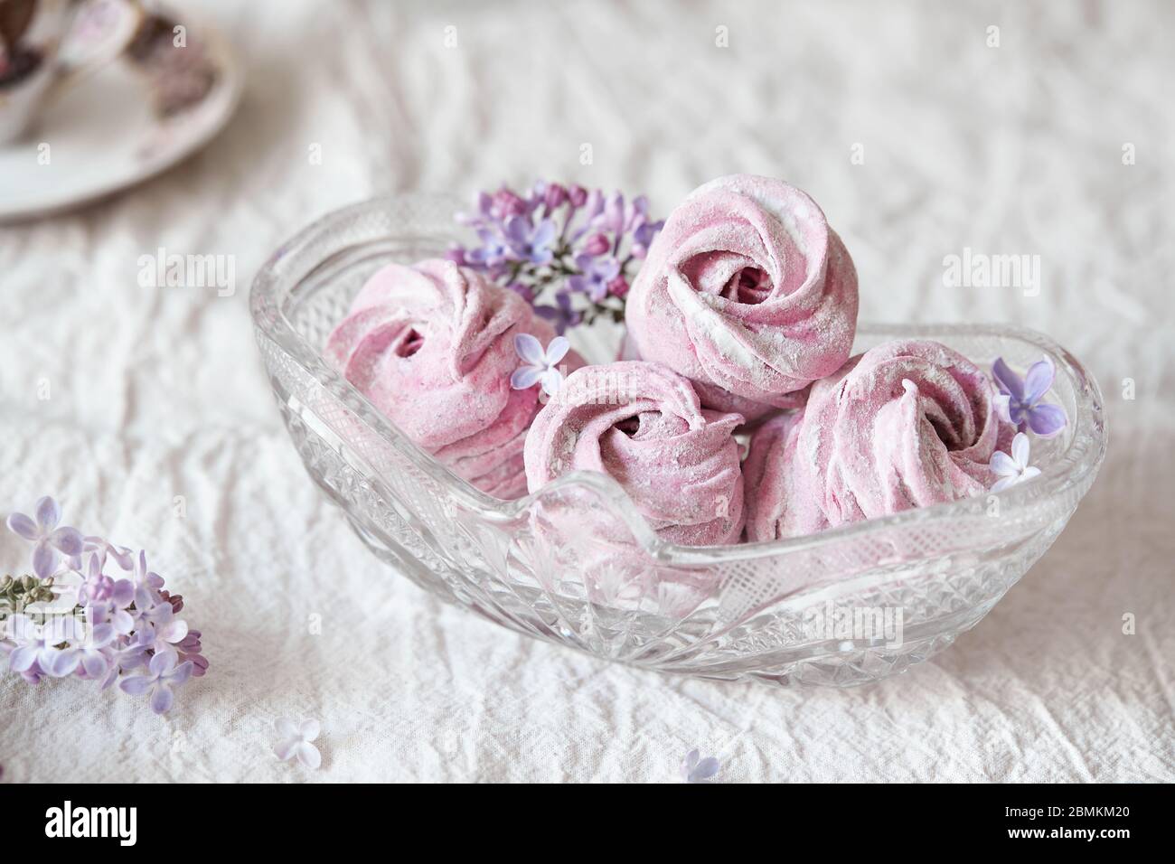 Violet doux fait maison Zephyr ou Marshmallow de cassis avec fleurs de lilas dans vase en verre sur toile blanche Banque D'Images