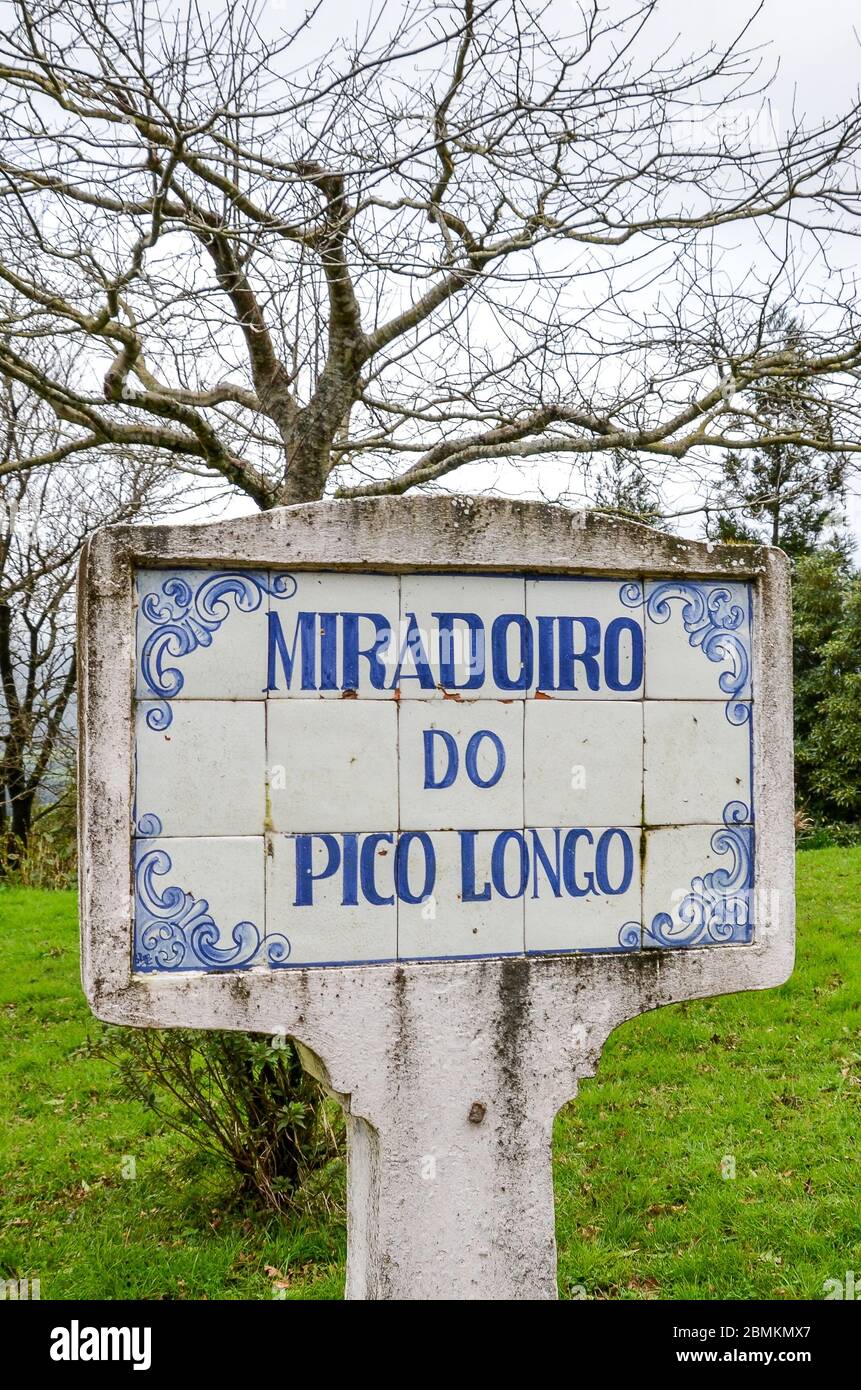 Signe bleu Miradoiro do Pico Longo, point de vue Pico Longo en anglais, sur des tuiles typiquement portugaises. Herbe et arbres sans feuilles en arrière-plan. Photo verticale. Banque D'Images
