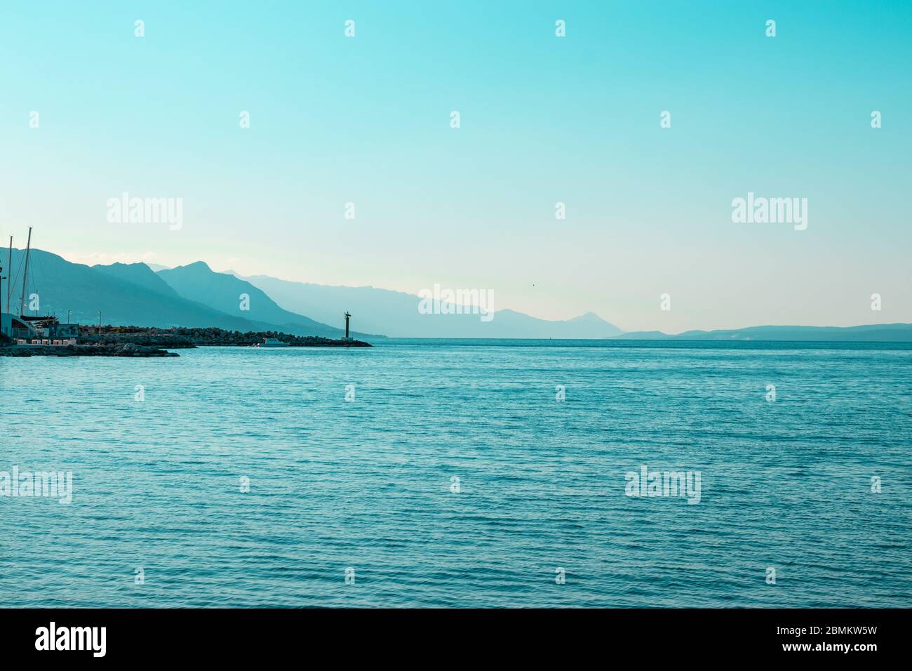 Lever du soleil bleu vif sur la rive de Split, phare au loin avec silhouettes de montagne allant au loin Banque D'Images