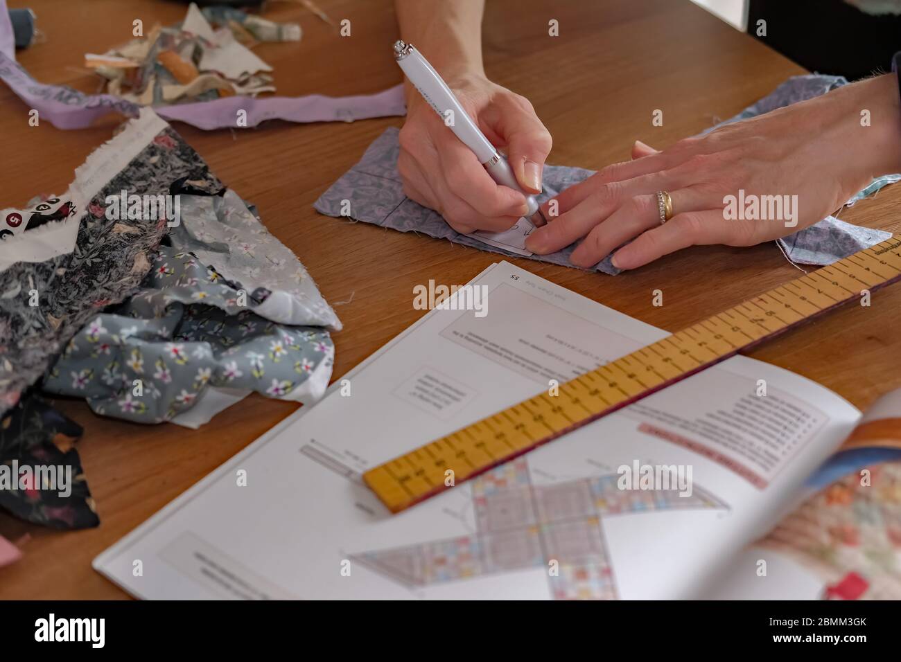 17 l'artisanat à la maison. Une femme de race blanche mesurant et marquant le tissu pour un projet de couture Banque D'Images