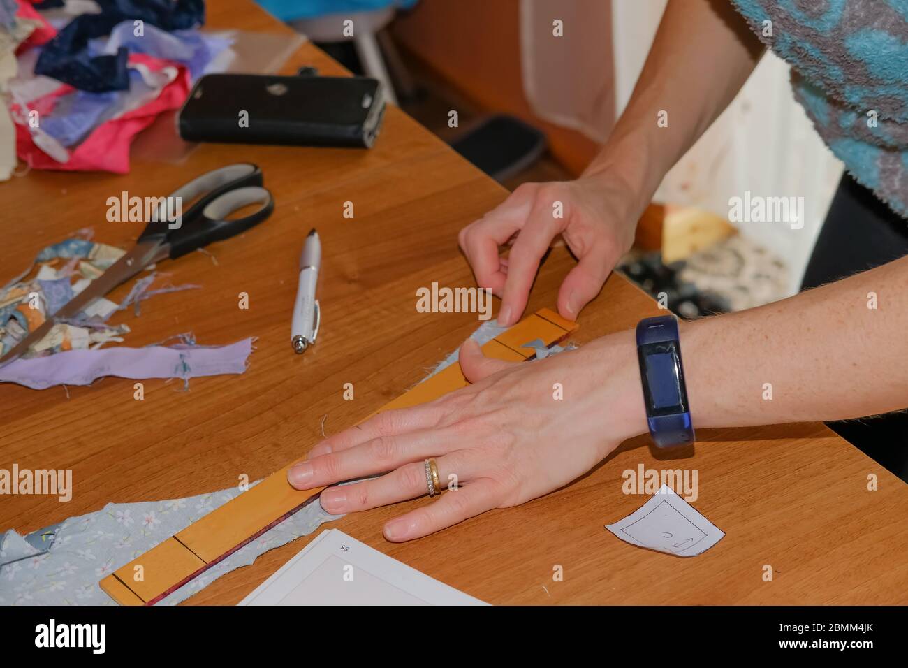 28 l'artisanat à la maison. Femme caucasienne non identifiable dessinant un motif sur un morceau de tissu sur une table en bois pendant un projet de couture à la maison Banque D'Images