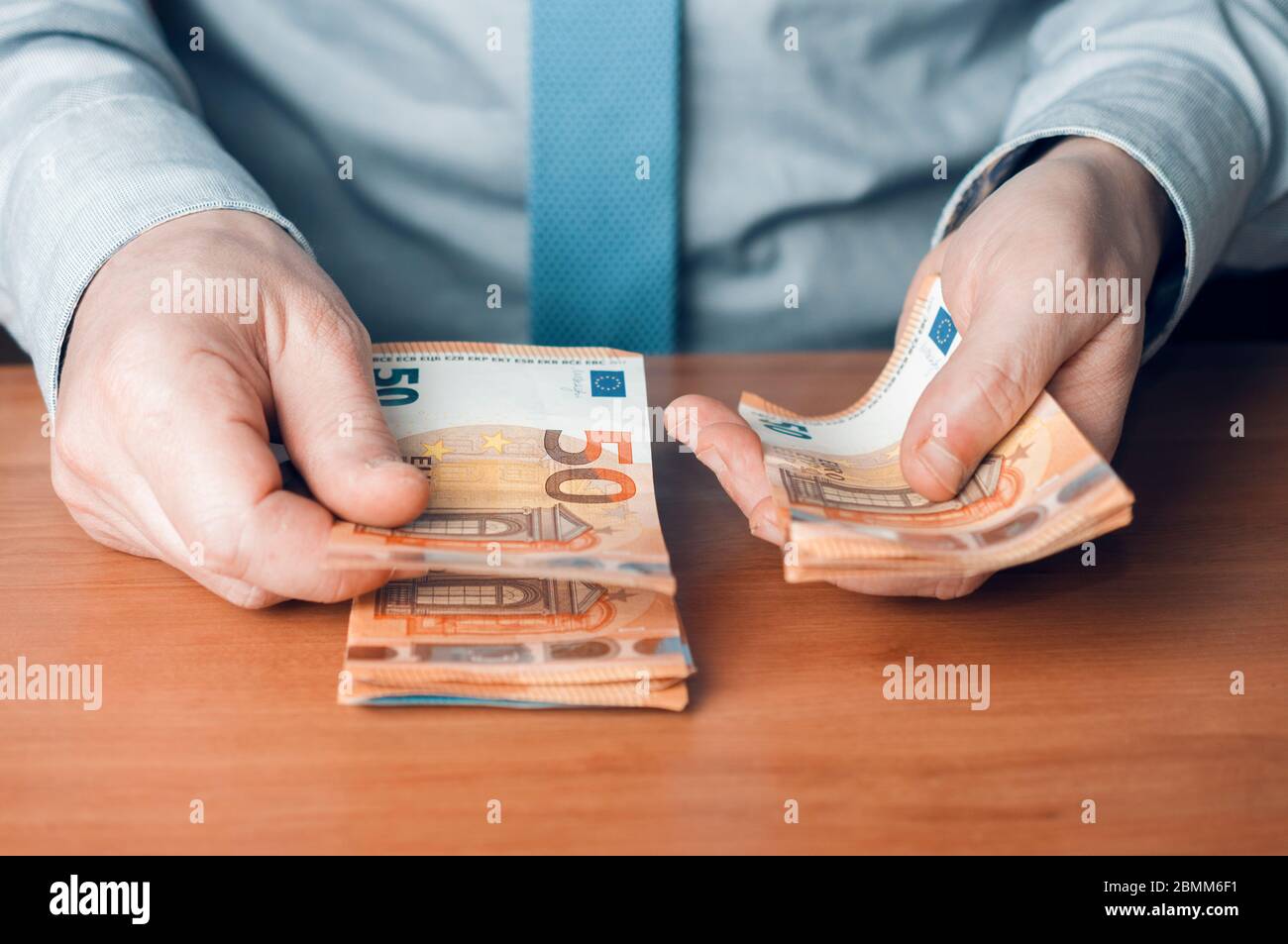 Le caissier de la banque compte les billets en euros sur un bureau en bois Banque D'Images