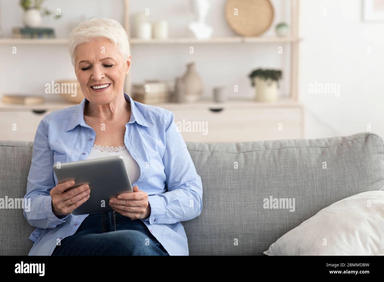 Loisirs de quarantaine pour les aînés. Une dame âgée regarde des films sur une tablette numérique Banque D'Images
