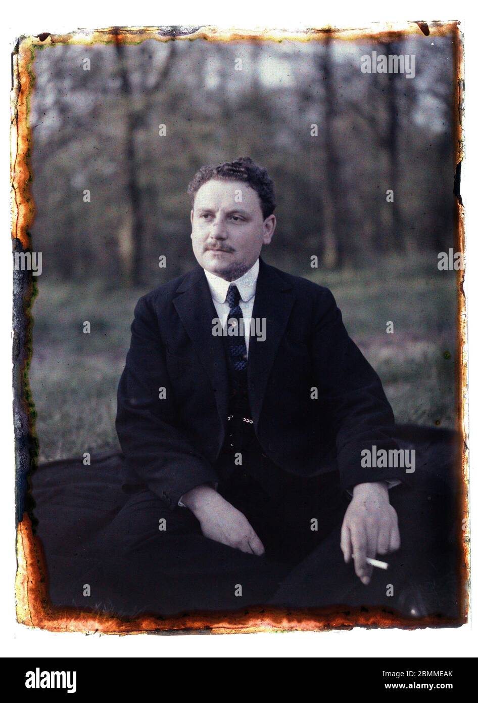 Portrait d'homme, riche père de famille parisien, ayant une cigarette à la main, il est assis dans un jardin en costume - 1920 environ (Portrait de a Banque D'Images