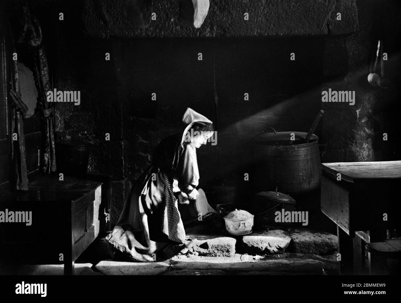 Une vieille cuisine sur le feu, dans une cuisine de ferme, Douarnenez, Bretagne, 1920 environ - Photographie vers 1920 - une vieille femme bloo Banque D'Images