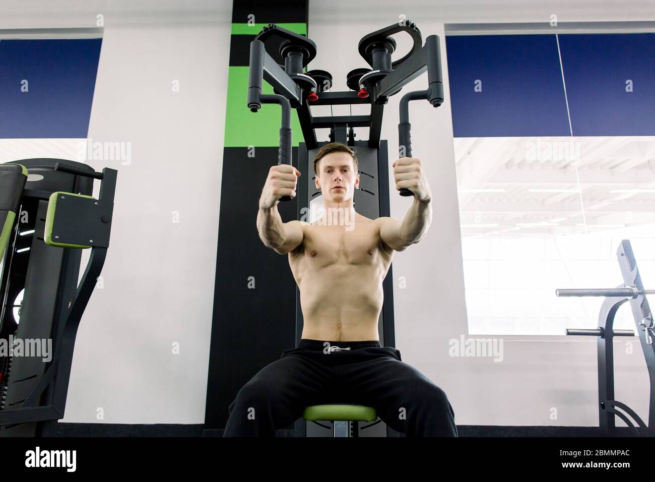 Bodybuilder posant dans la salle de gym. Un homme musclé qui s'efforce de faire de l'exercice à la salle de gym. Entraînement sans chemise. Exercices de poitrine. Entraînements de poitrine. Banque D'Images