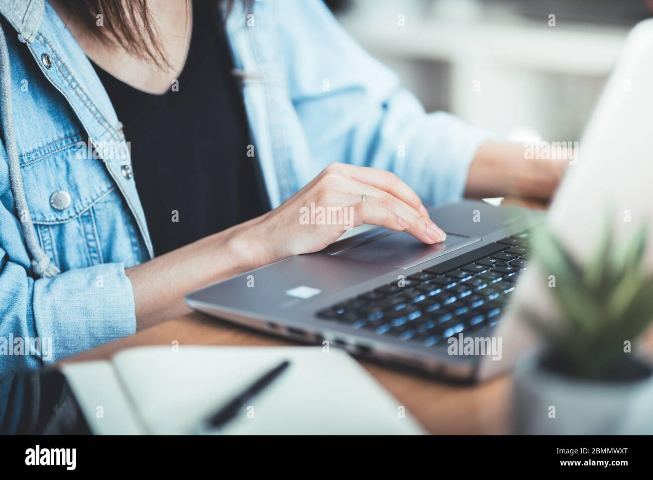 Image rognée d'une femme travaillant au bureau via un ordinateur portable, jeune femme gestionnaire utilisant un ordinateur portable tout en étant assise au bureau, lumière de torche, travail. Banque D'Images
