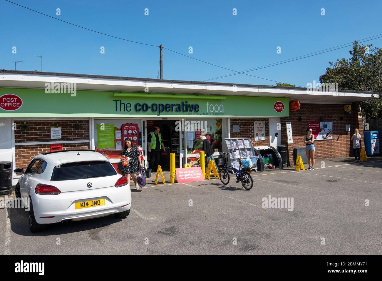 Stone, Buckinghamshire, Royaume-Uni. 9 mai 2020. Magasin de proximité de cuisine coopérative Village. File d'attente de la boutique en observant les distances sociales comme demandé par avis. Membre du personnel se trouvant à l'entrée du magasin et contrôlant la petite file d'attente. Voir l'image 2BMMY78 pour le lapsus résultant de la distanciation sociale. Crédit : Stephen Bell/Alay Banque D'Images