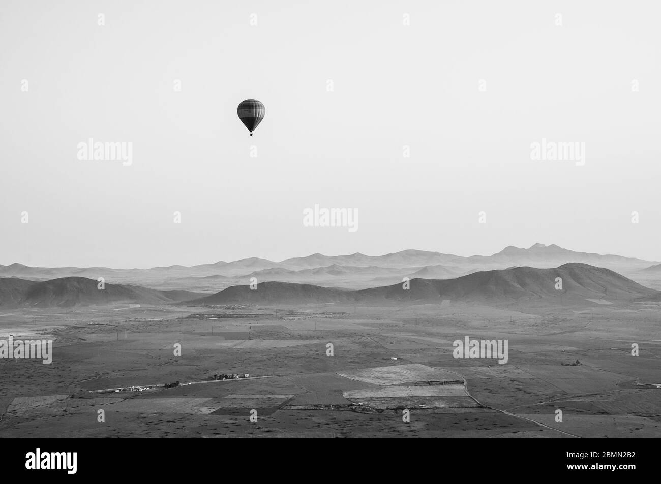 Photo en noir et blanc de style rétro d'une montgolfière au-dessus du maroc. Belles montagnes de l'Atlas au loin, avec un autre ballon dans le ciel. Banque D'Images