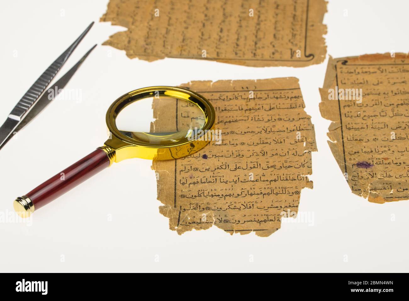 Livre pages avec un manuscrit arabe sur une table avec une lumière et une loupe. Paléographie, l'étude de l'écriture arabe ancienne Banque D'Images