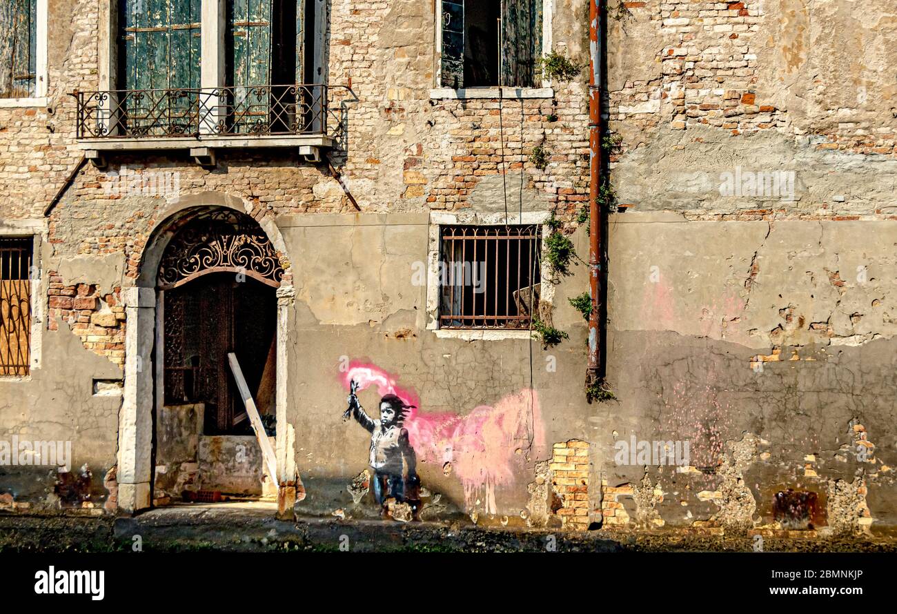 Une peinture murale Banksy représentant un enfant migrant tenant une éruption rose, sur un bâtiment à côté d'un canal dans le quartier Dorsoduro de Venise, Italie Banque D'Images