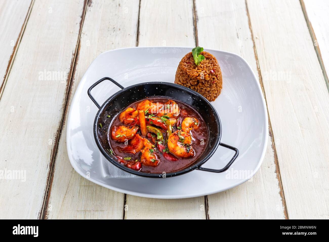 Crevettes à la sauce tomate dans une casserole. Garnir, riz aux herbes. Banque D'Images