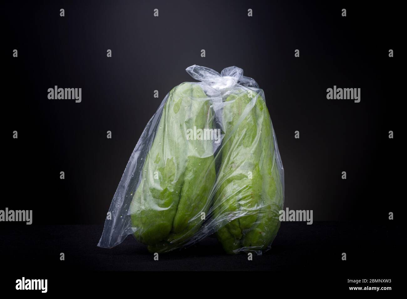 Légumes Chayote vert vif emballés dans du plastique provenant d'un marché brésilien local. Les aliments de studio à faible teneur en clés continuent de vivre sur fond gris foncé. Banque D'Images