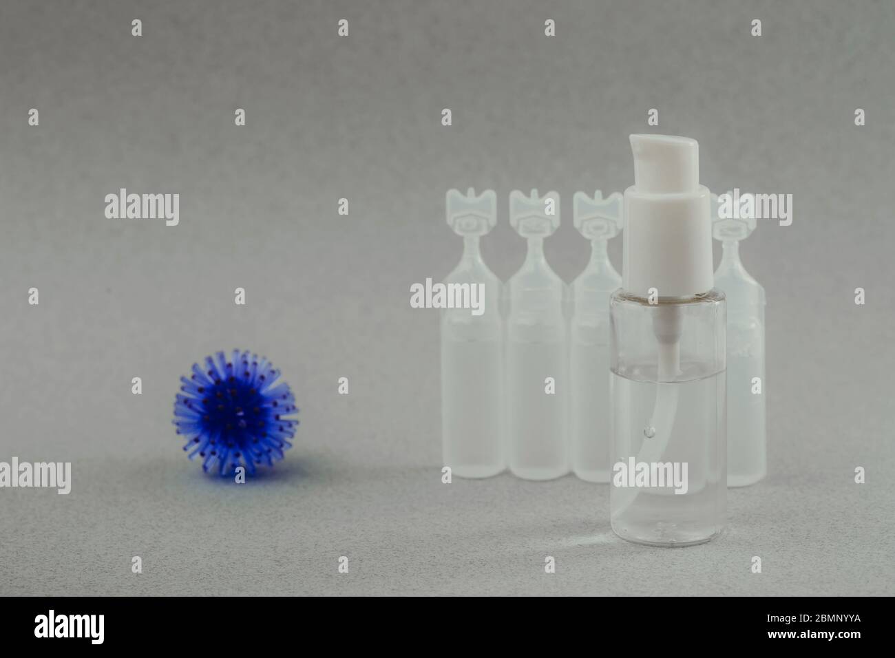Modèle abstrait du coronavirus, ampoule avec médicament et flacon avec gel antibactérien pour les mains sur fond gris. Concept d'hygiène. Banque D'Images