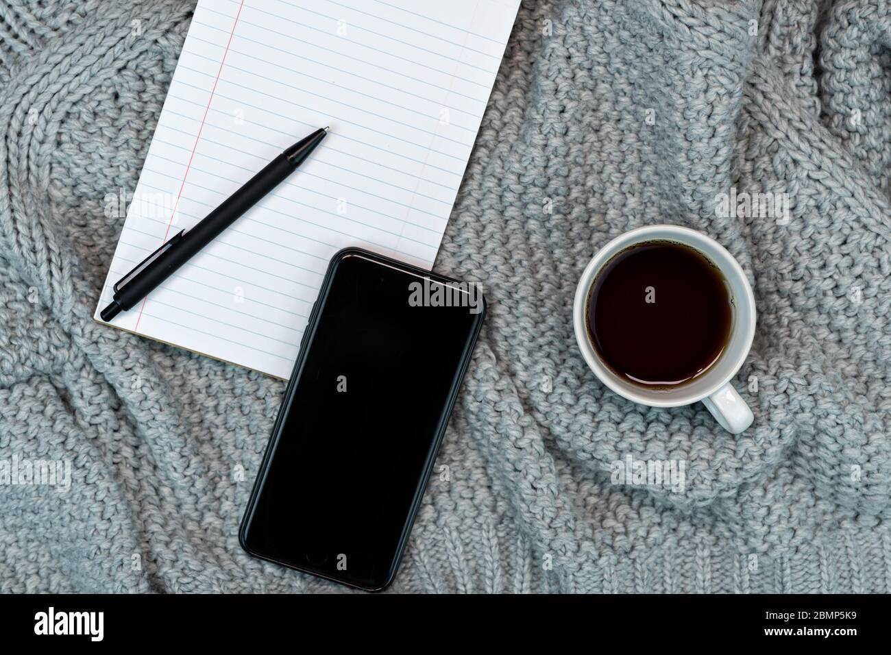 Bureau confortable, café en pull, bloc-notes, téléphone, bureau à la maison. Concept chaud par temps froid. Banque D'Images