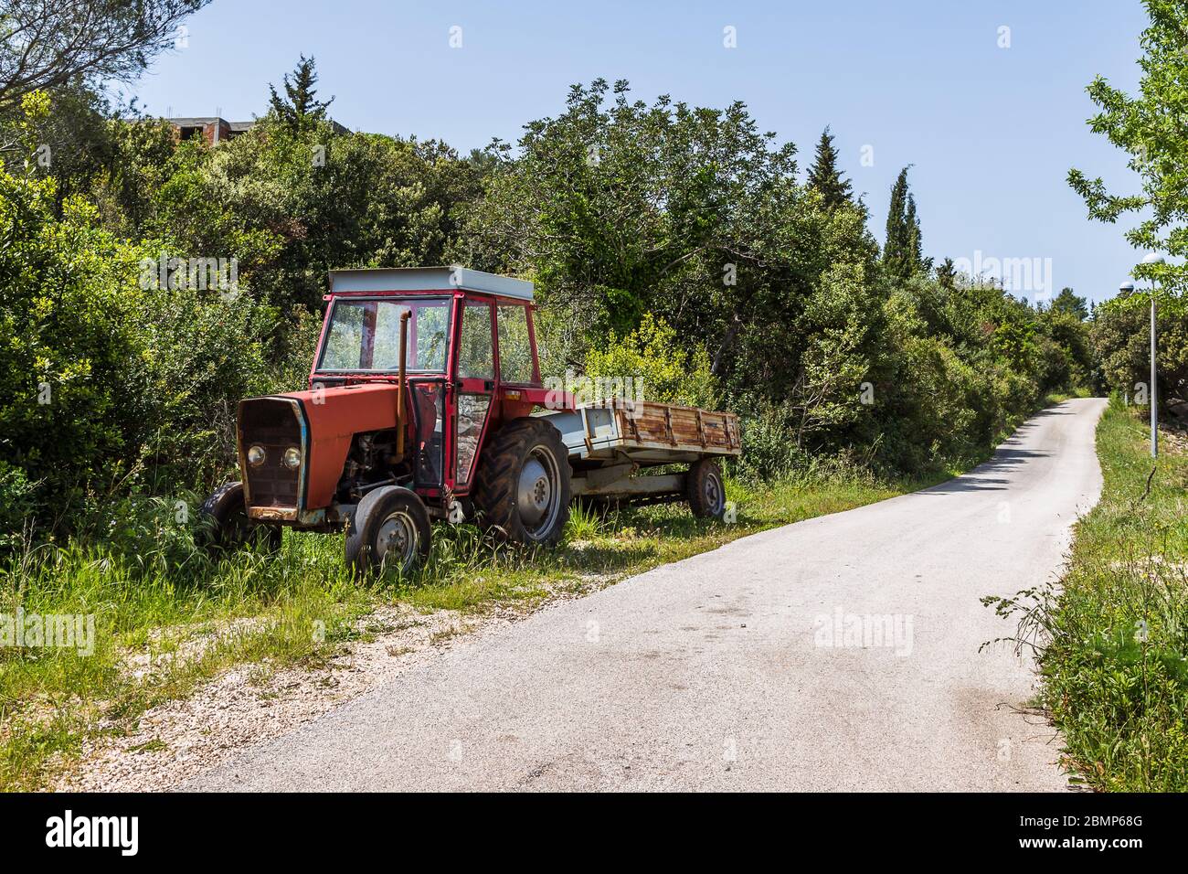 Vieux tracteur rouge sur l'île de Sipan stationné sur le côté d'une route. Banque D'Images