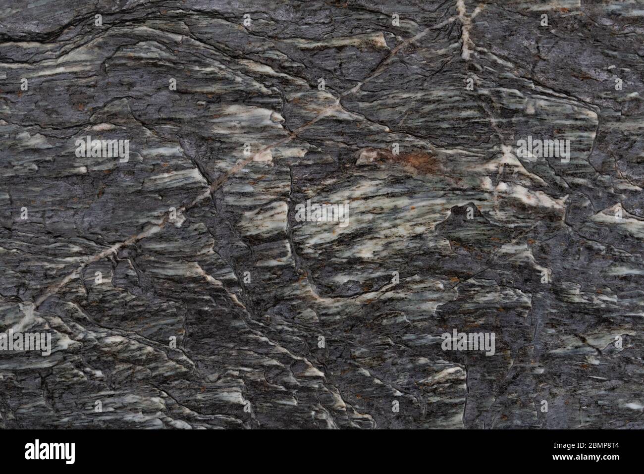 Arrière-plan abstrait de la surface rugueuse de roche sombre texturée avec des lignes et des inlay blancs Banque D'Images
