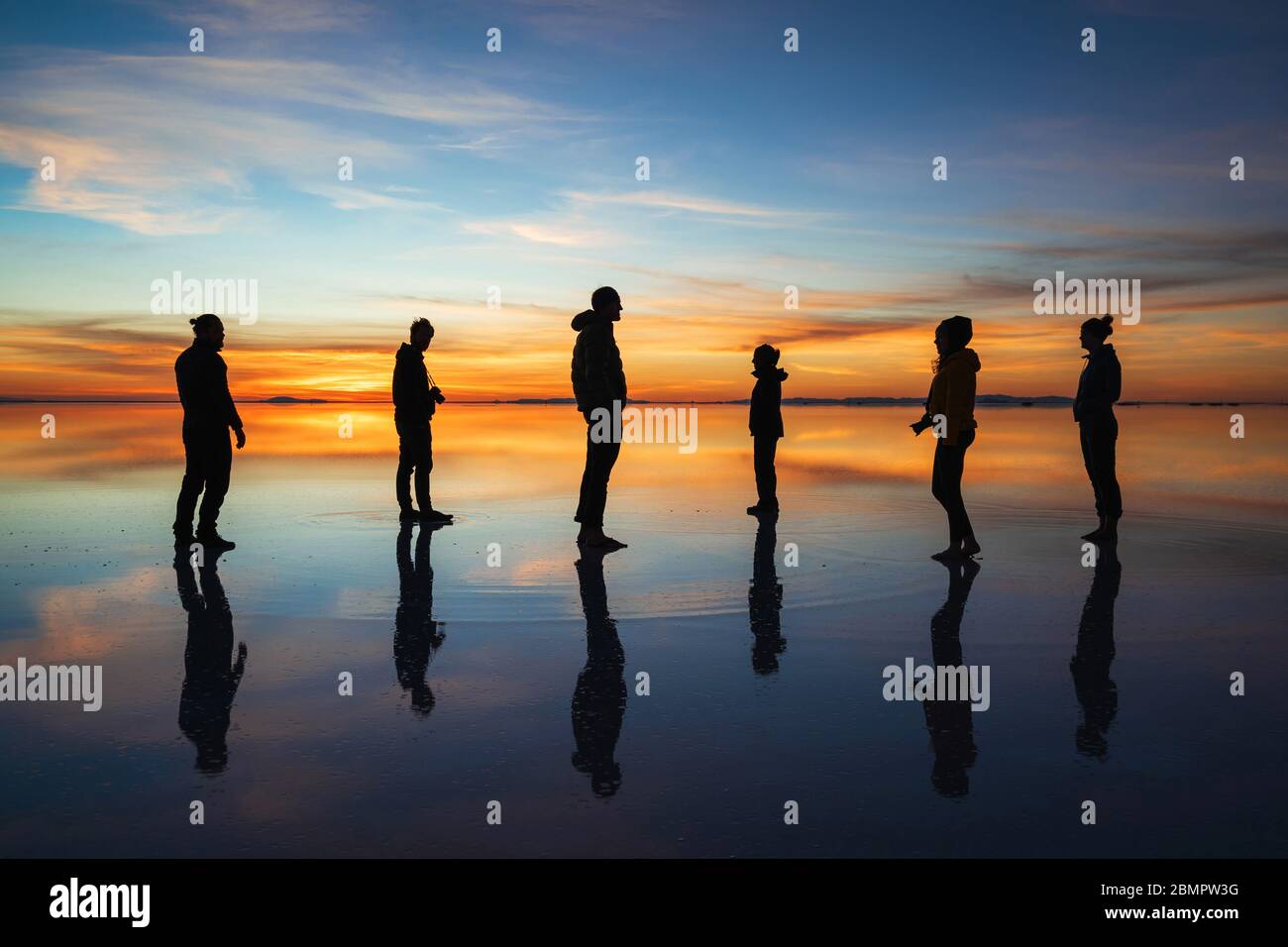 Silhouette de jeunes touristes contre le lever du soleil à Uyuni Salt Flats (Espagnol: Salar de Uyuni) en Bolivie, Amérique du Sud. Banque D'Images