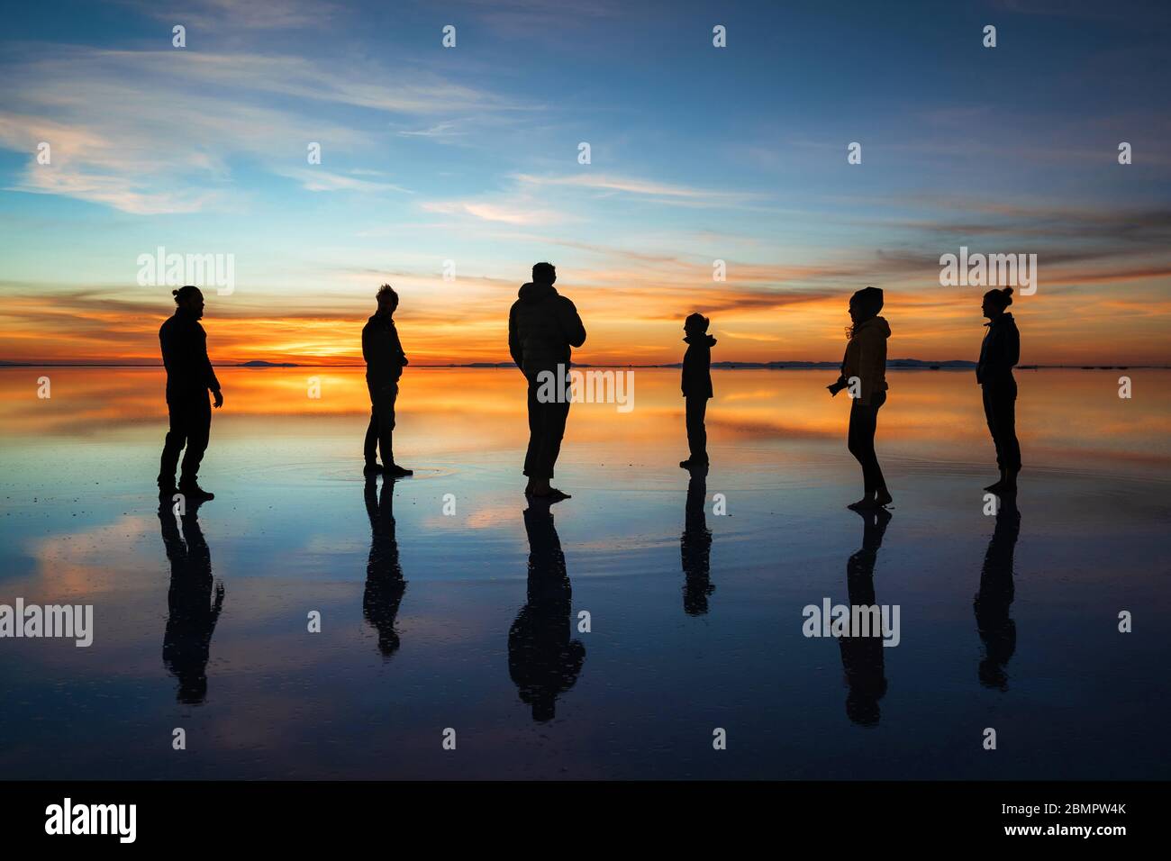 Silhouette de jeunes touristes contre le lever du soleil à Uyuni Salt Flats (Espagnol: Salar de Uyuni) en Bolivie, Amérique du Sud. Banque D'Images