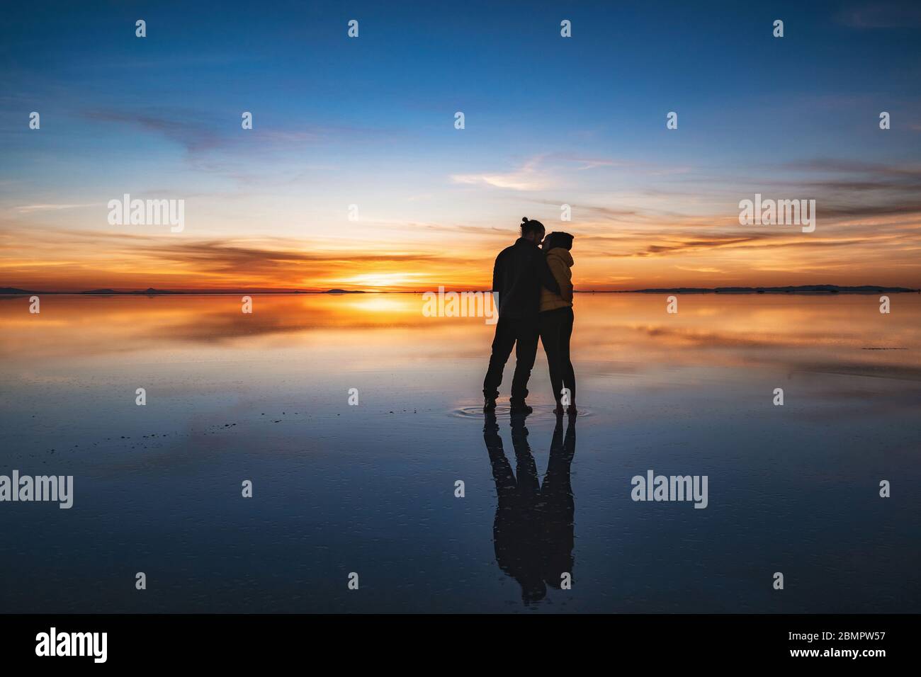 Jeune couple regardant le lever du soleil à Uyuni Salt Flats (Espagnol: Salar de Uyuni) en Bolivie, Amérique du Sud, vacances romantiques et lune de miel concept. Banque D'Images
