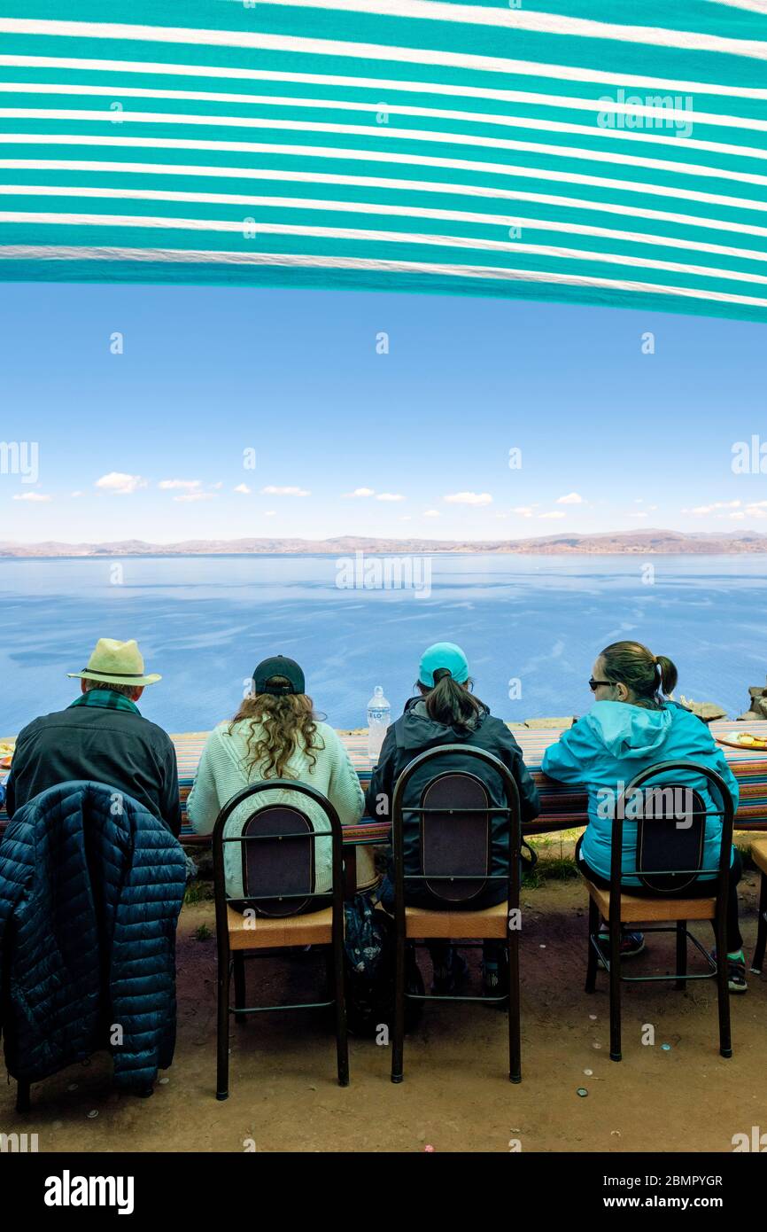 Groupe de touristes qui mangent le déjeuner dans un restaurant local avec vue sur le lac Titicaca, île Taquile Pérou Banque D'Images
