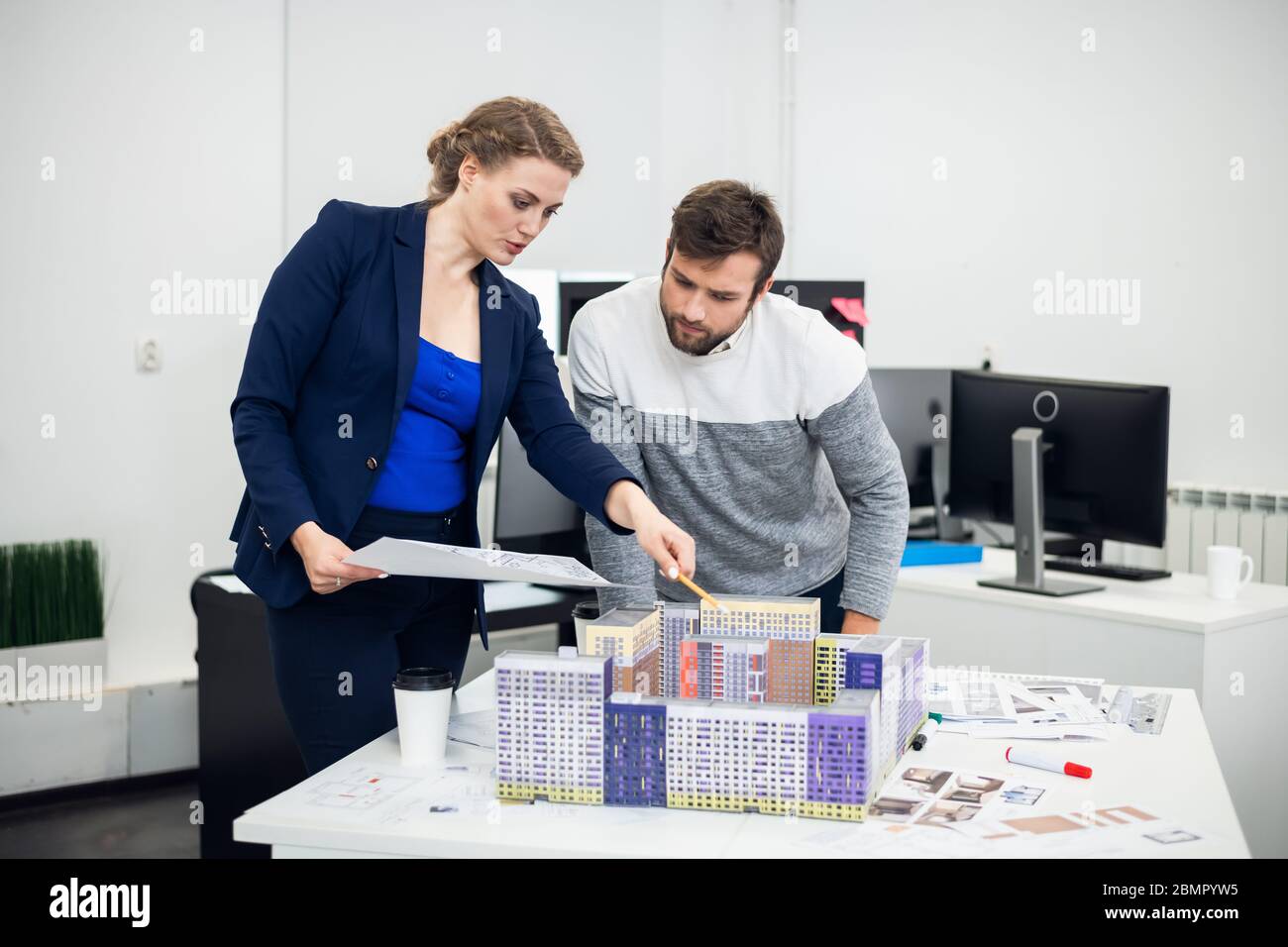Les jeunes employés du bureau d'architecte discutant du mod de construction Banque D'Images