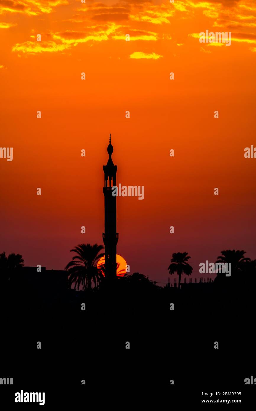 Soleil se levant au-dessus de l'horizon derrière le minaret d'une mosquée dans la campagne de Louxor Banque D'Images
