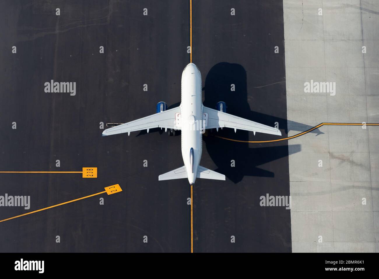 Vue aérienne d'un avion blanc moyen avec lignes de direction de l'aéroport comme arrière-plan. Avion non identifié vu d'en haut. Espace pour le texte. Banque D'Images