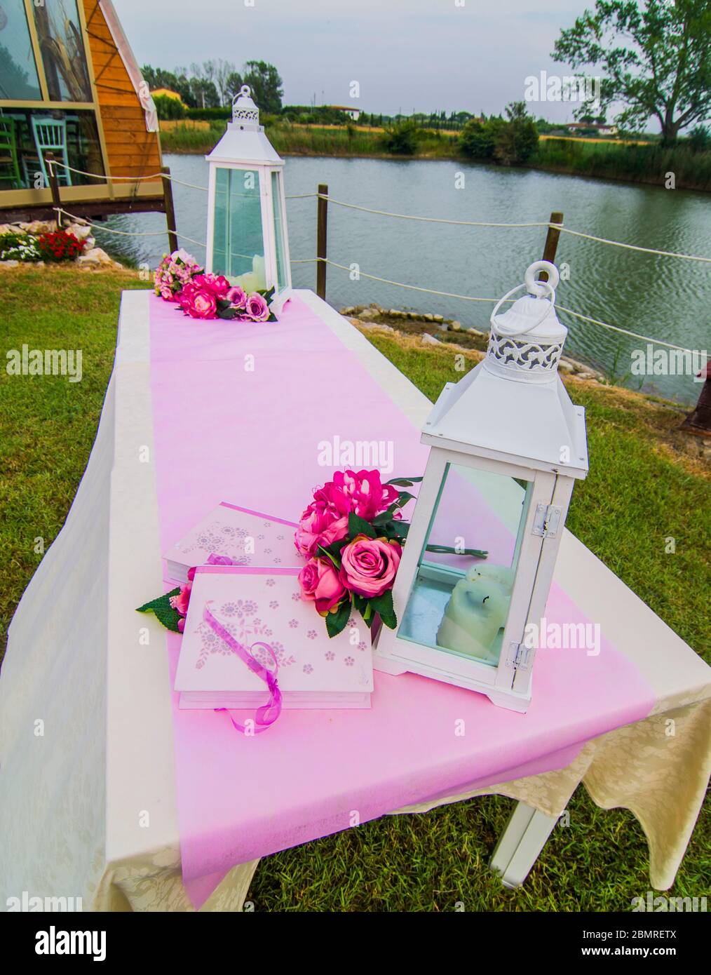 table extérieure décorée dans des tons de blanc, de rose et de fuchsia avec des bougies et des fleurs parfumées pour votre fête Banque D'Images table extérieure décorée dans des tons de blanc, de rose et de fuchsia avec des bougies et des fleurs parfumées pour votre fête Banque D'Images