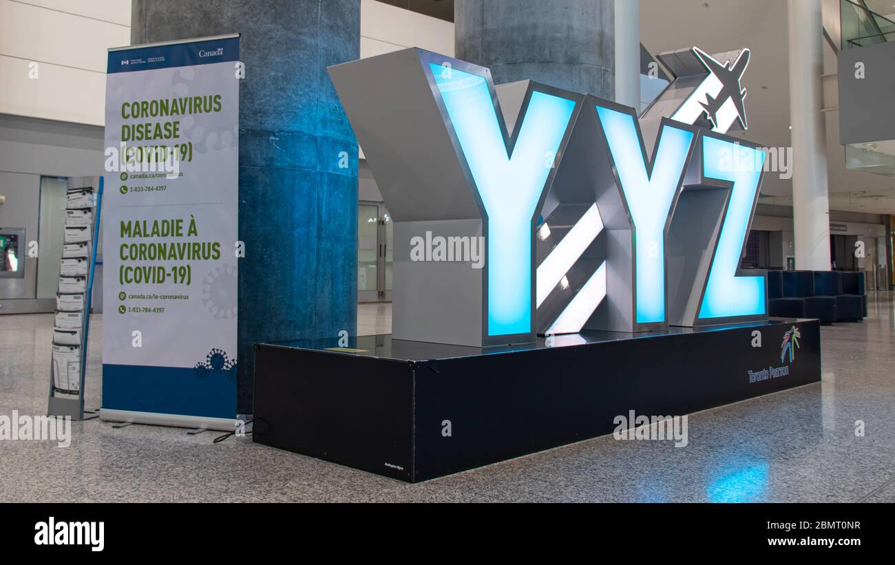 Panneau YYZ à l'intérieur de l'aéroport Pearson de Toronto avec panneau d'information sur la maladie à coronavirus (COVID-19) placé à côté. Banque D'Images