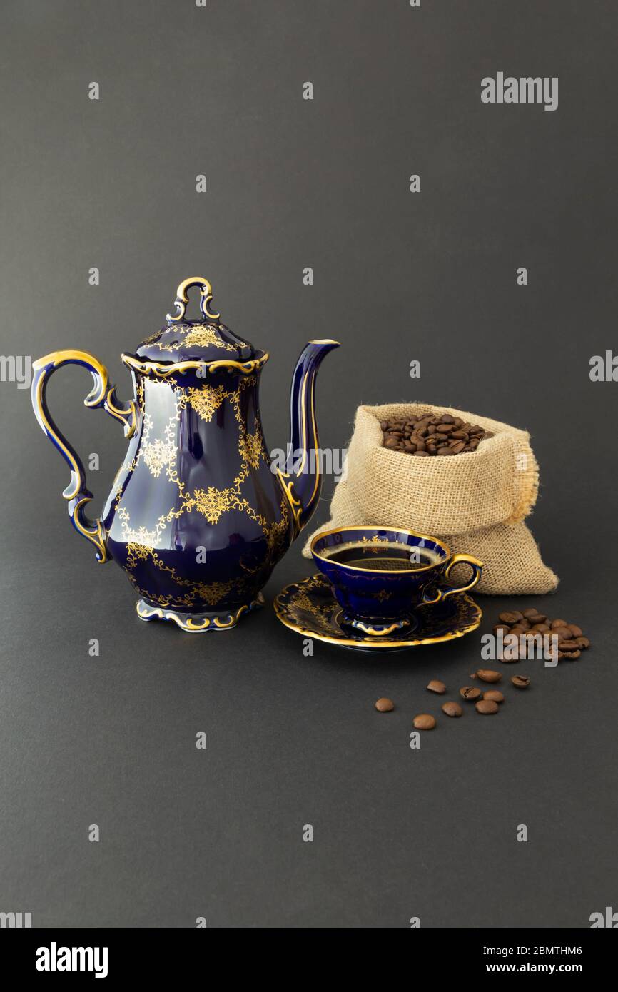 Encore plus de vie avec un café en porcelaine d'époque bleu cobalt à motif floral doré et une bourre de grains de café torréfiés Banque D'Images