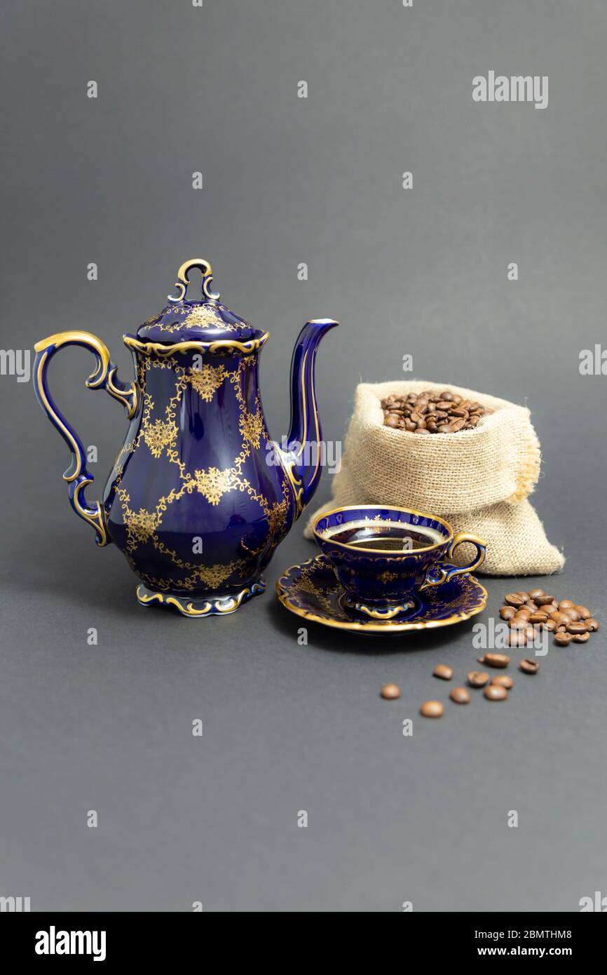 Encore plus de vie avec un café en porcelaine d'époque bleu cobalt à motif floral doré et une bourre de grains de café torréfiés Banque D'Images