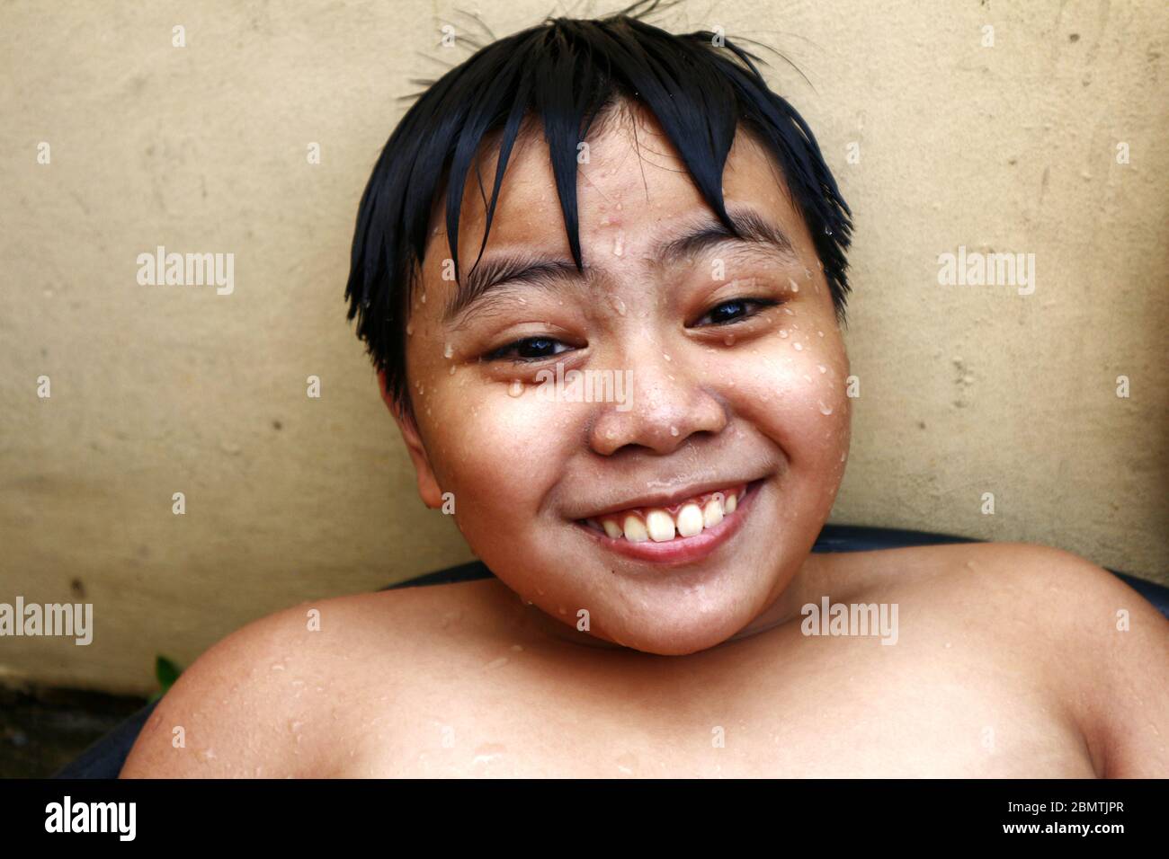 Portrait d'un jeune garçon asiatique humide souriant à l'appareil photo Banque D'Images