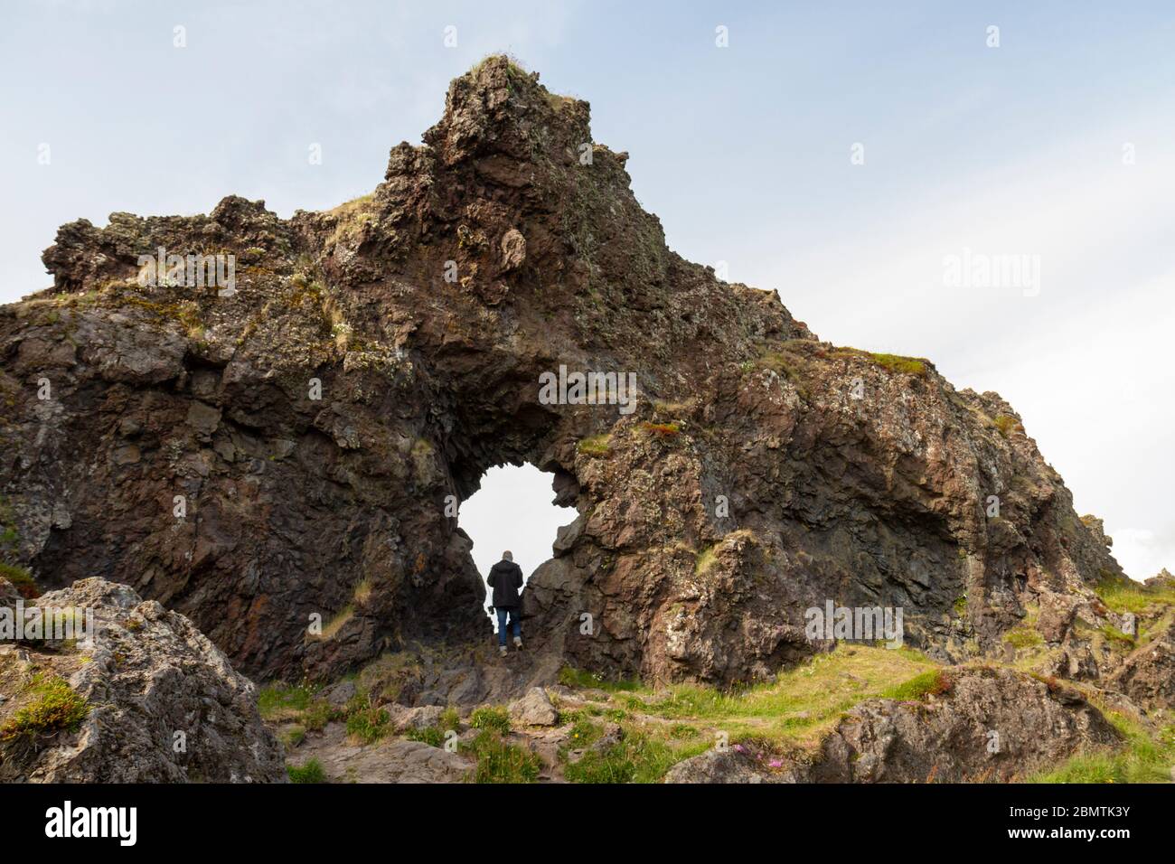 Un visiteur qui marche à travers une structure de lave près de Djúpalónssandur, une plage de sable noir au pied de Snæfellsjökull, péninsule de Snæfellsnes, Islande. Banque D'Images