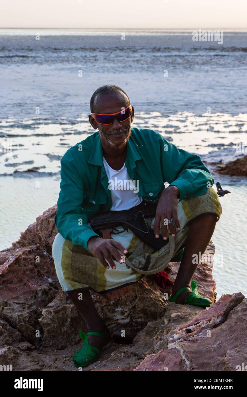 Dallol, Ethiopie - novembre 2018: Scout local posant avec le fusil avec le lac salé dans le désert de Danakil en arrière-plan Banque D'Images