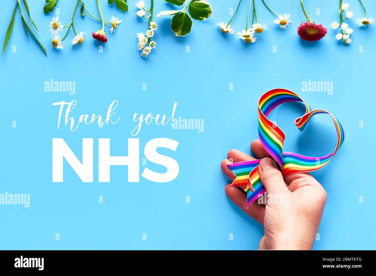 Merci NHS, médecins, infirmières, équipes médicales et travailleurs clés en Angleterre et au Royaume-Uni! Main tenant le ruban arc-en-ciel en forme de coeur sur fond bleu menthe wi Banque D'Images