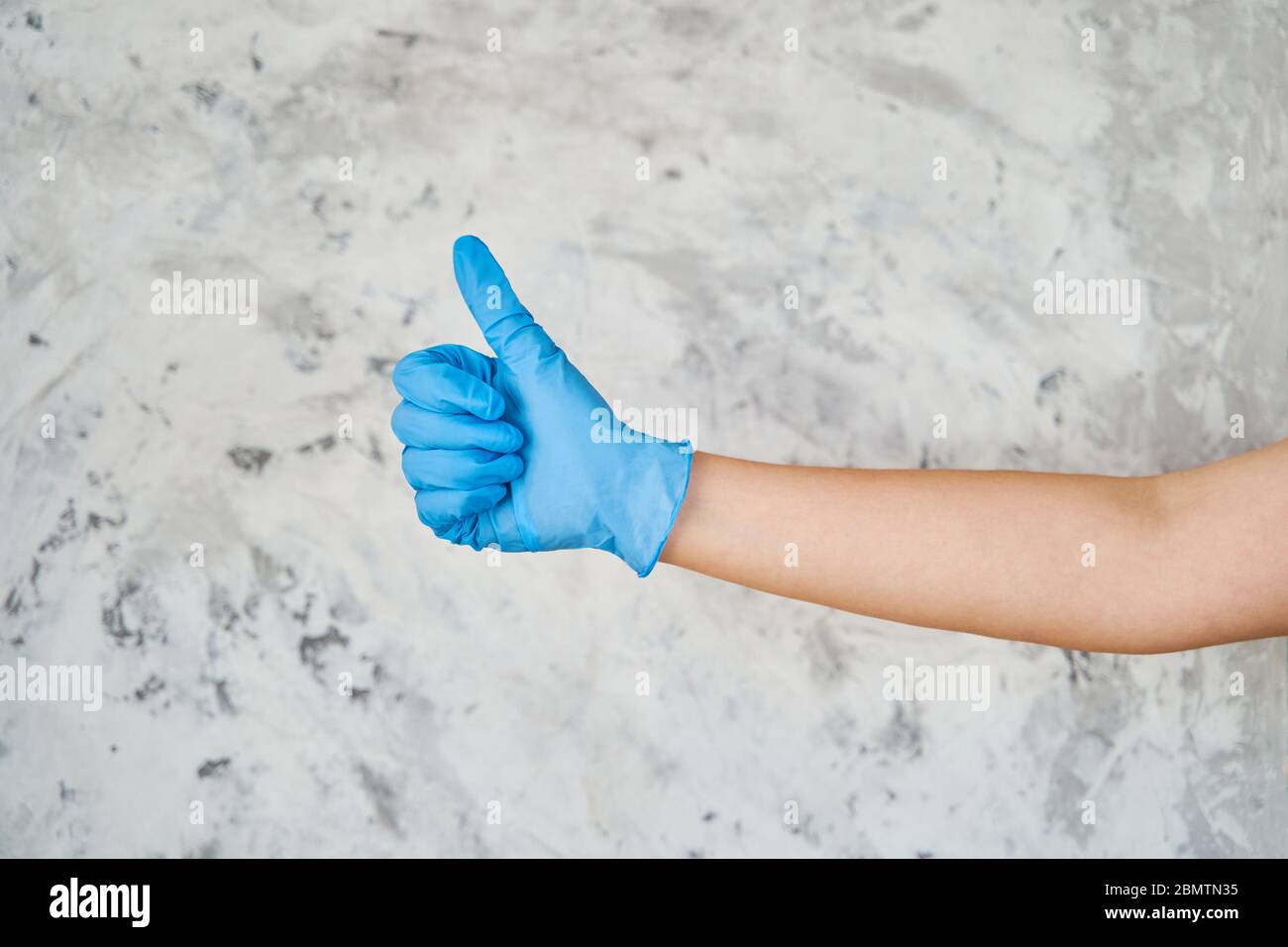 une fille dans un gant bleu montre un signe comme Banque D'Images