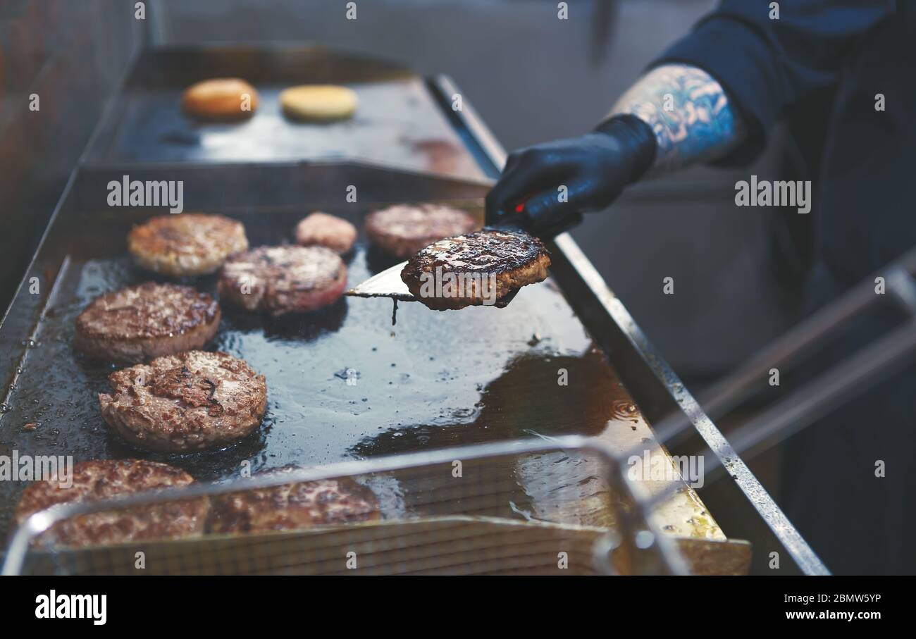 Chef cuisinant des hamburgers.Professional cuisez la viande de bœuf sur une poêle dans la cuisine du restaurant.Worker cuising burgers.Kitchen employee préparant des côtelettes de porc Banque D'Images