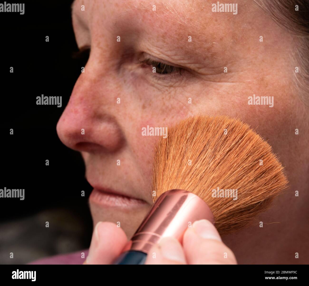 Femme qui pose le maquillage du visage Banque D'Images