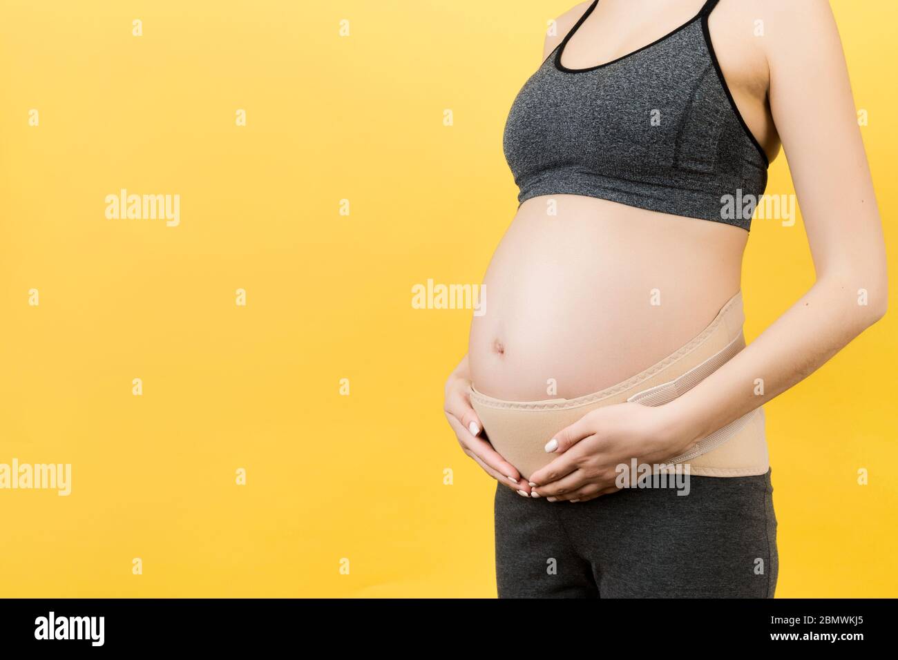 Gros plan du bandage de grossesse habillé sur la femme enceinte pour  réduire les douleurs dorsales sur fond jaune avec l'espace de copie.  Ceinture de soutien orthopédique abdominale Photo Stock - Alamy