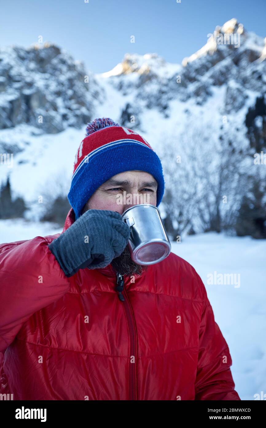 Le meilleur homme avec barbe est de boire du thé ou du café à partir de la tasse dans les montagnes en hiver. Camping La montagne concept. Banque D'Images