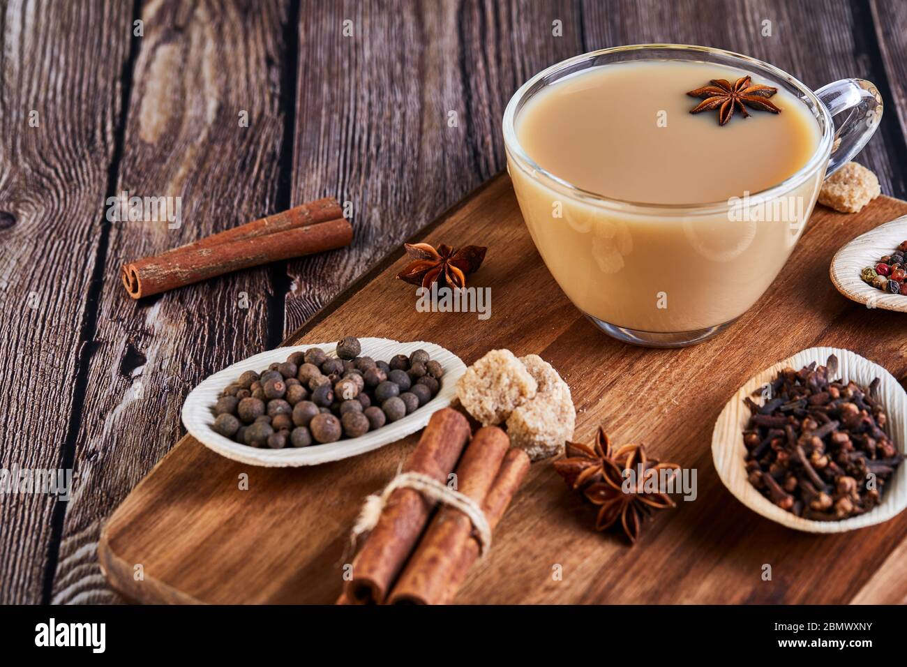 Boisson traditionnelle indienne - thé masala aux épices. Cannelle, cardamome, anis, sucre, clous de girofle, poivre sur fond de bois sombre. Copier l'espace. Vue latérale Banque D'Images